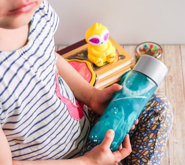 child playing with sensory bottle in calm down corner