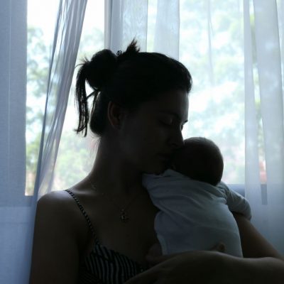 Mother holding newborn against a window
