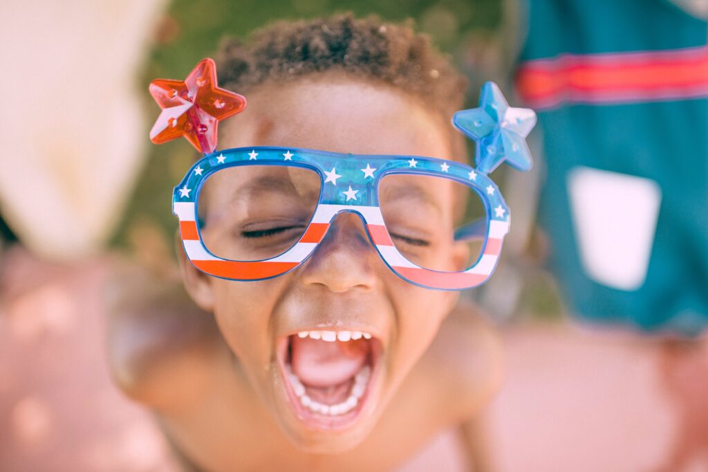 Close-up of a happy child wearing fun glasses and smiling big for the camera.