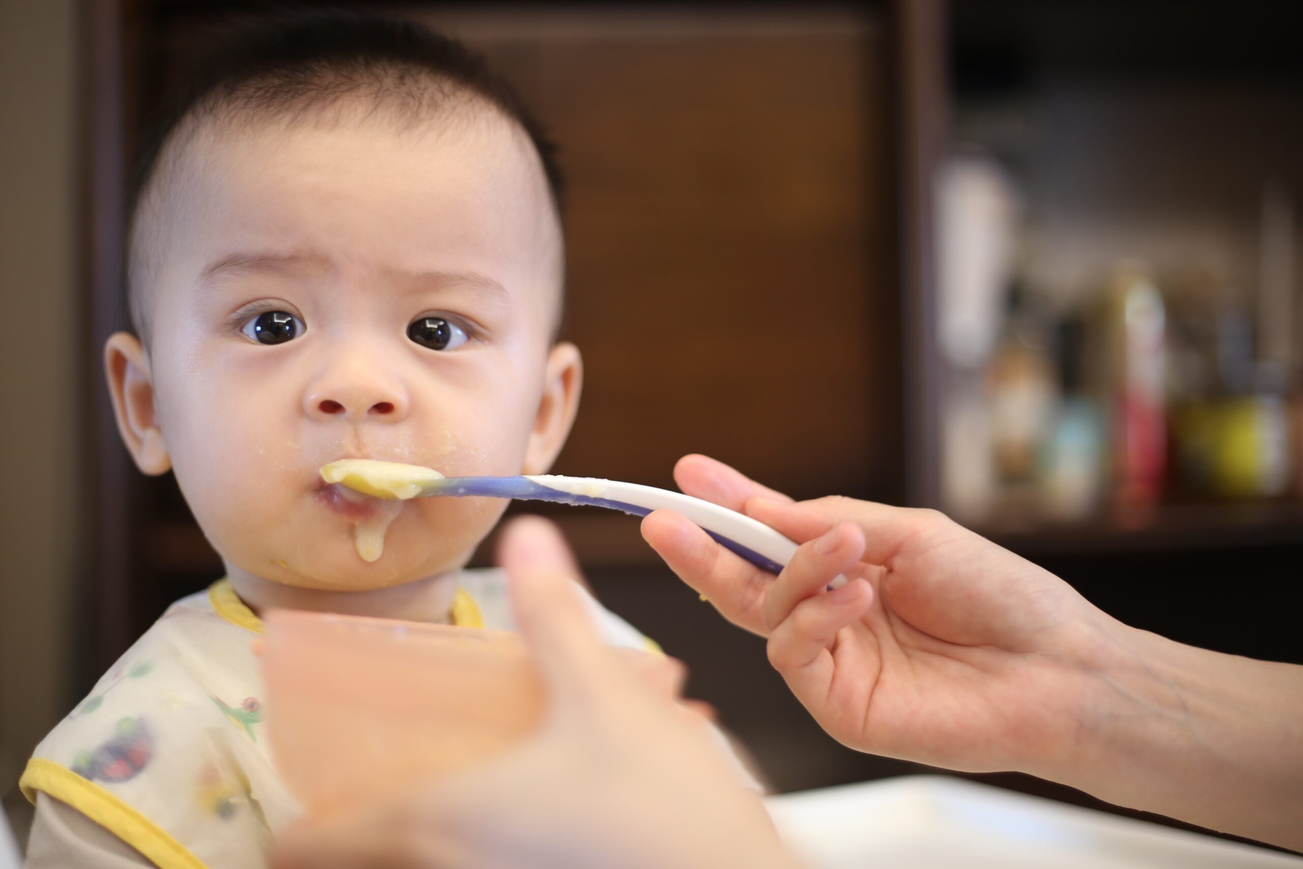 Baby being fed food from a spoon.