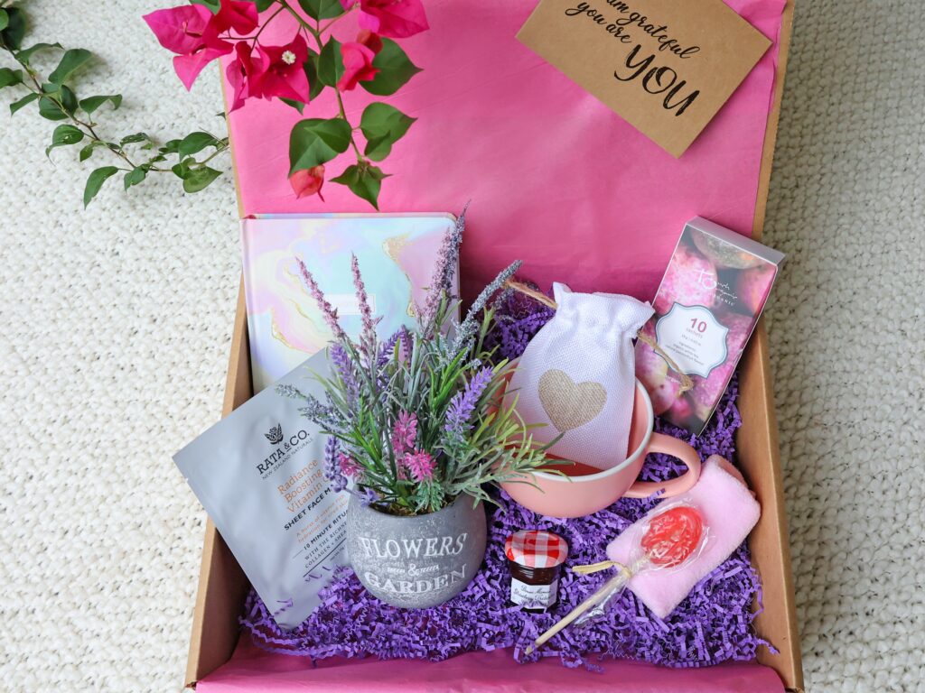 gift box containing lavender flowers , a notebook, jam, and candies